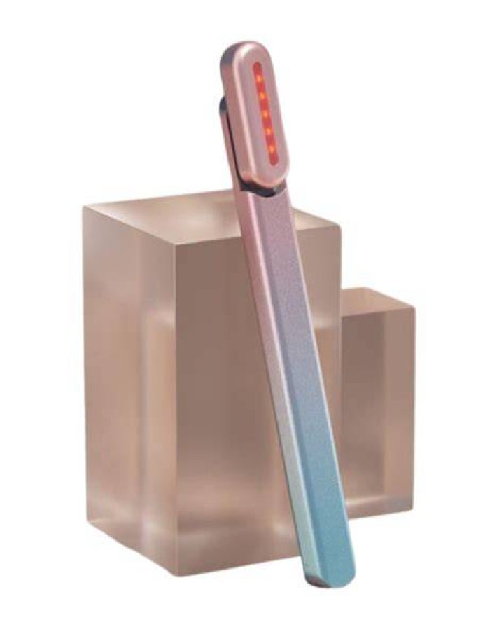 A Solawave wand leaning against a pink stand