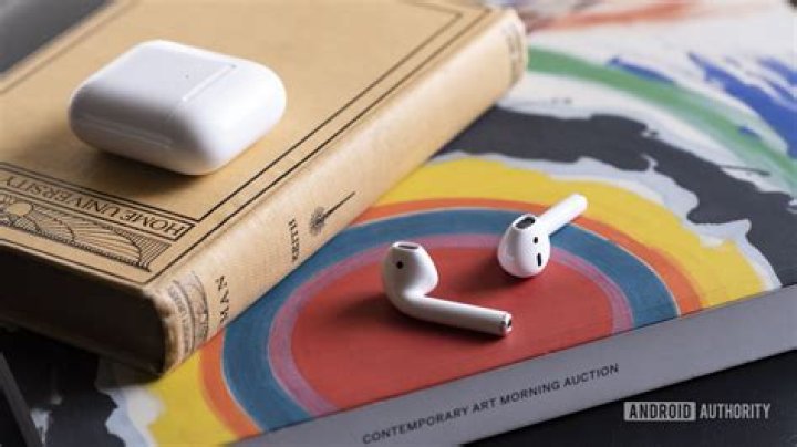 Apple new AirPods 2_earbuds case separate Apple new AirPods 2 outside of the case resting on a book.