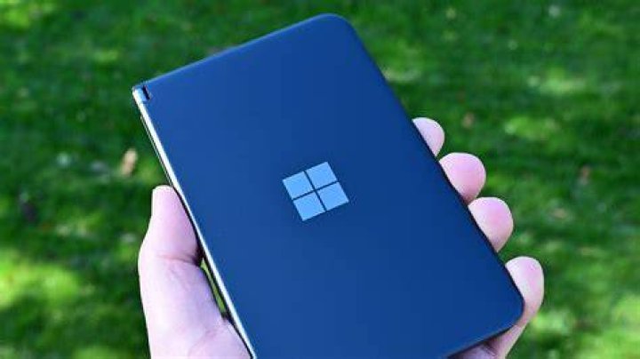 Microsoft Surface Duo closed in hand against backdrop