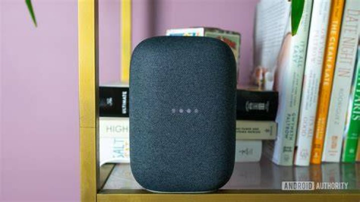 Google Nest Audio hotword LED lights The gray Google Nest Audio on a bookshelf with the lights blinking.